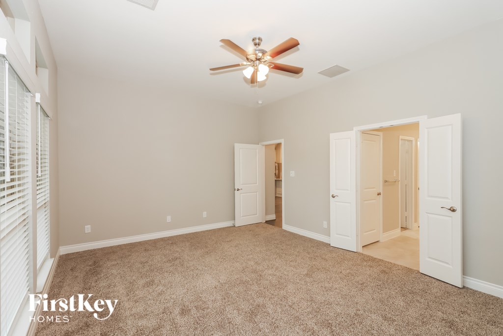 A spacious room with a ceiling fan and carpeted floor.