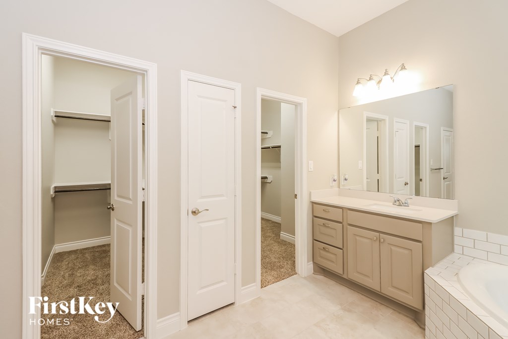 A bathroom with a tub, sink, and mirror.
