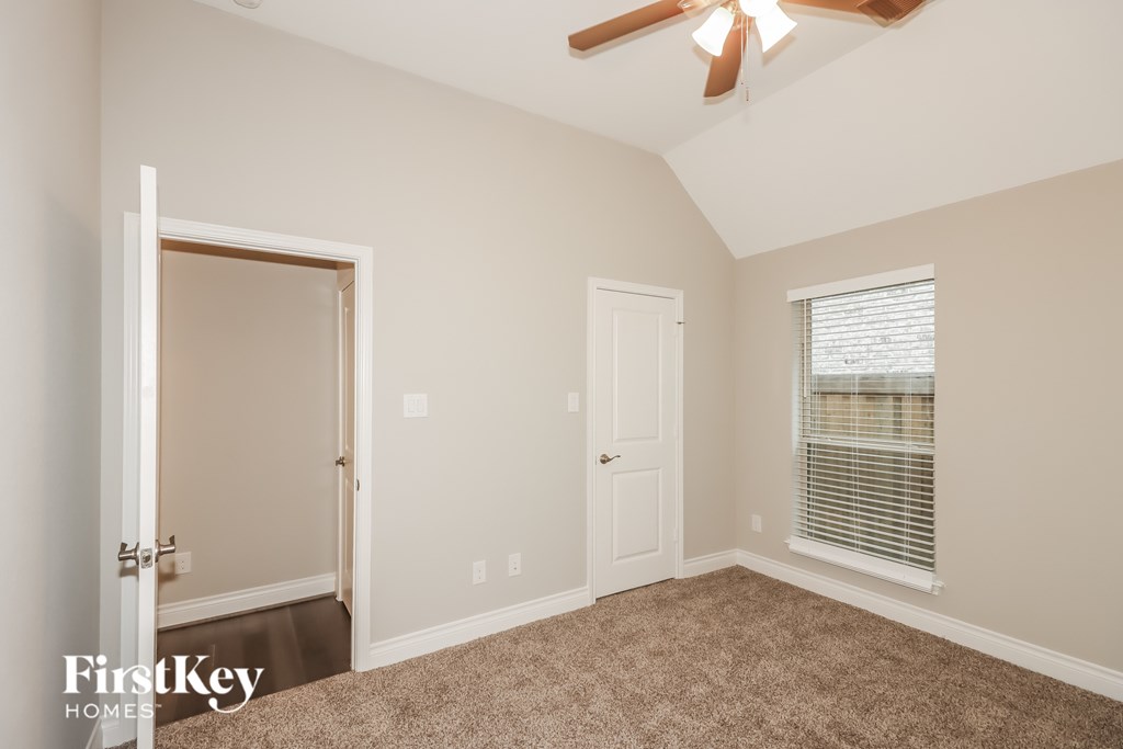 A room with a carpeted floor and a ceiling fan.