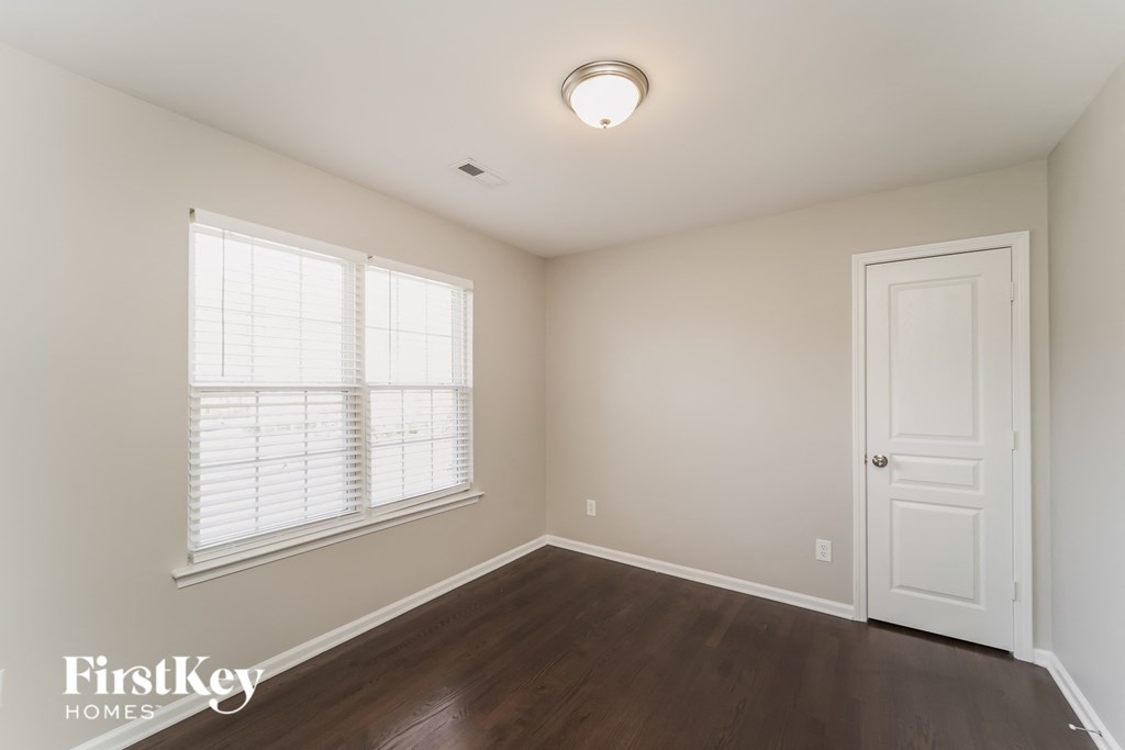 a bedroom with wood flooring and a white door and window