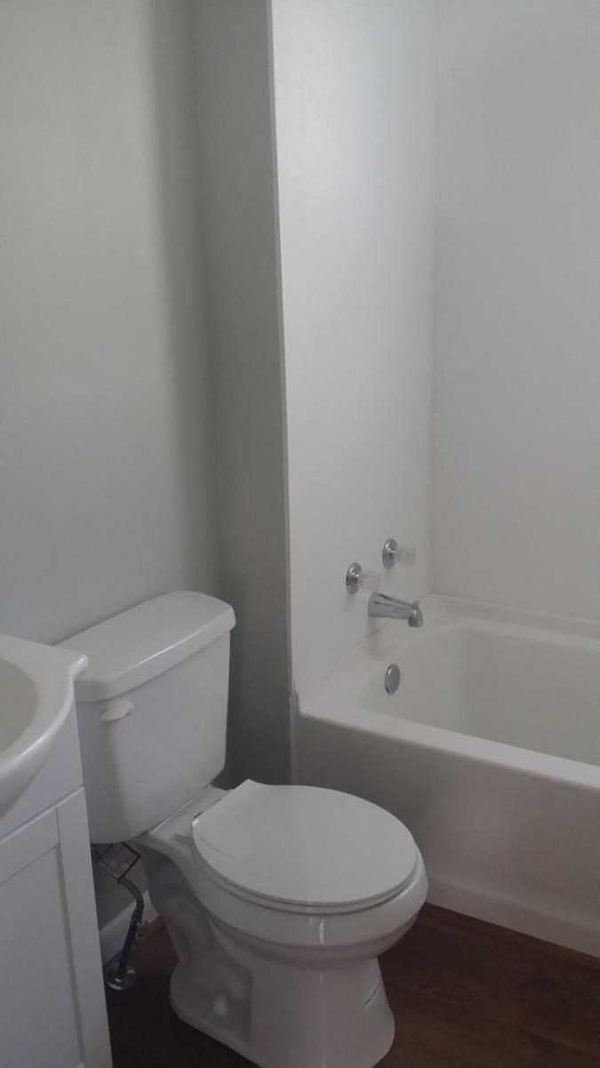 a white bathroom with a toilet and a bath tub