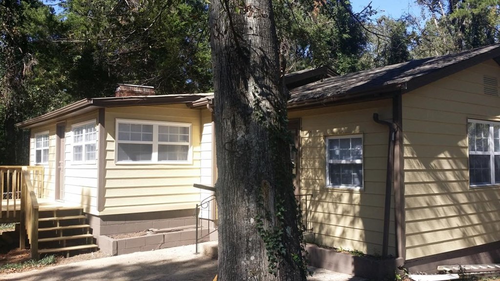 a small yellow house with a tree in front of it
