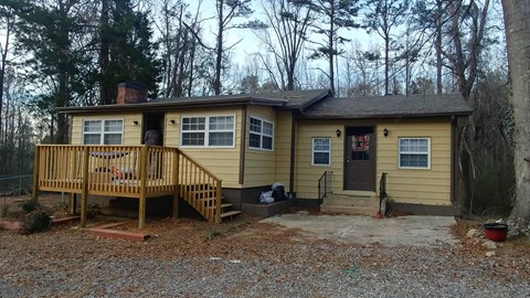 a yellow house with a porch and a deck