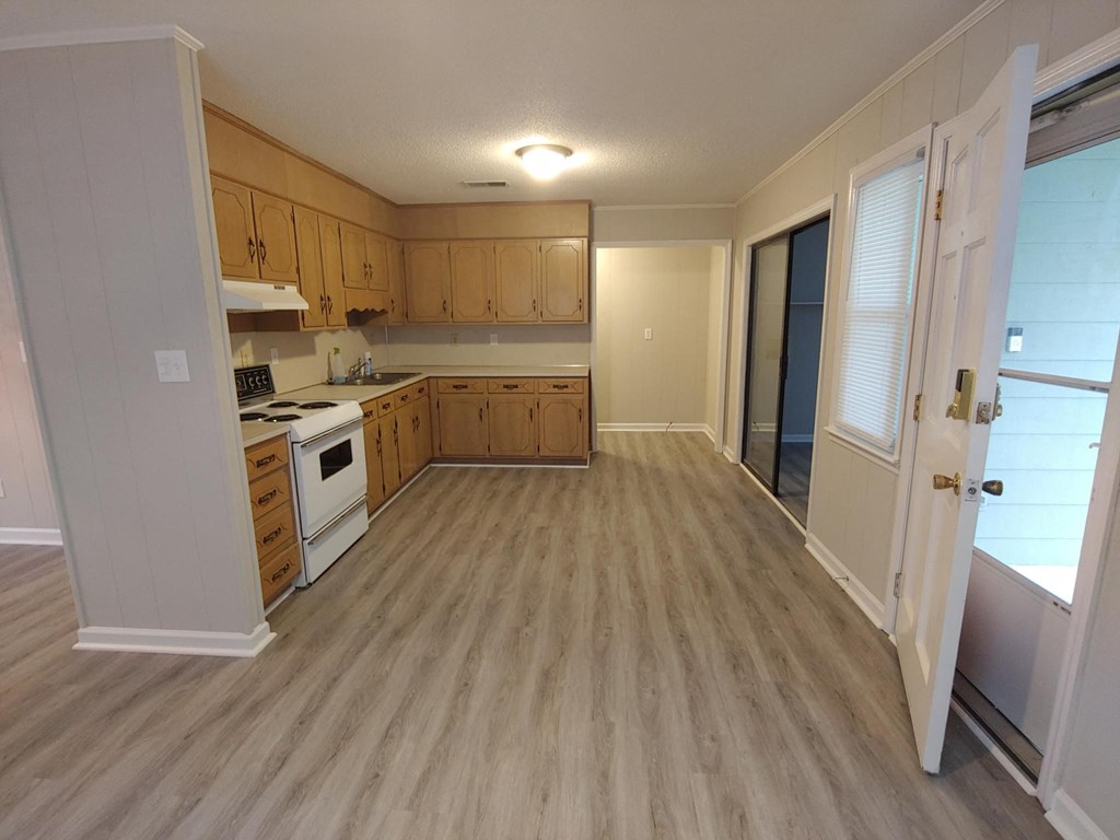 A kitchen with wooden cabinets and a white stove top oven.