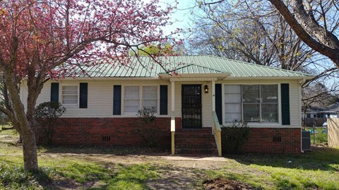 a small white house with a tree in front of it