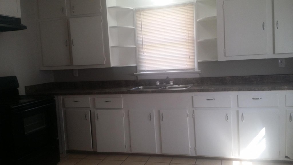 an empty kitchen with white cabinets and a sink
