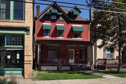 the front of a red brick house with green awnings