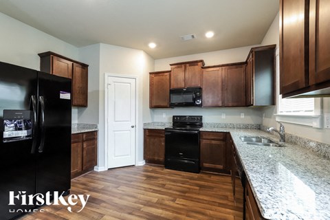 a kitchen with wooden cabinets and granite counter tops and black appliances