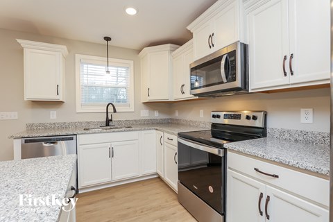 A kitchen with white cabinets and a granite countertop.