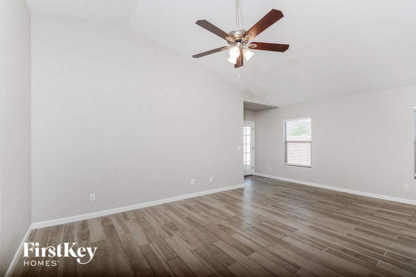 an empty living room with a ceiling fan and wood floors