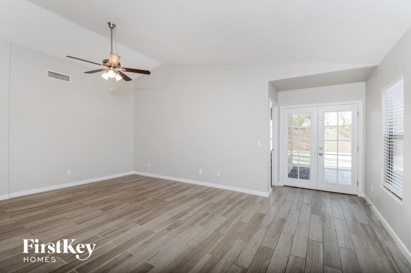 an empty living room with wood flooring and a ceiling fan