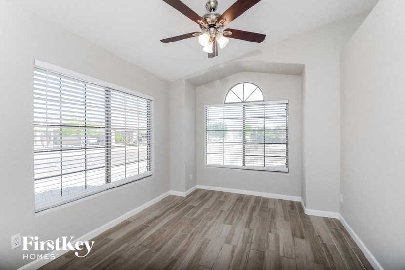 an empty living room with a ceiling fan and a window