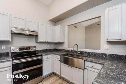 a kitchen with white cabinets and stainless steel appliances and a sink
