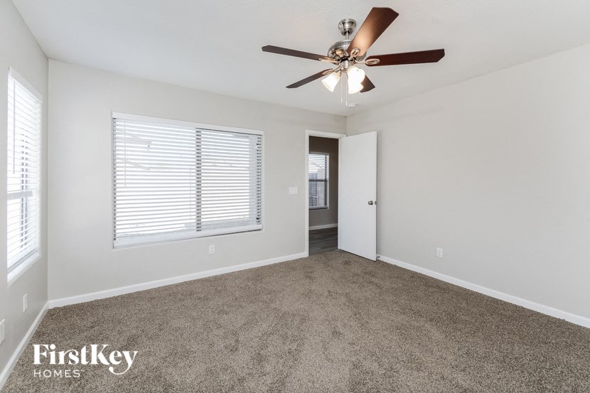 an empty living room with a ceiling fan and a window