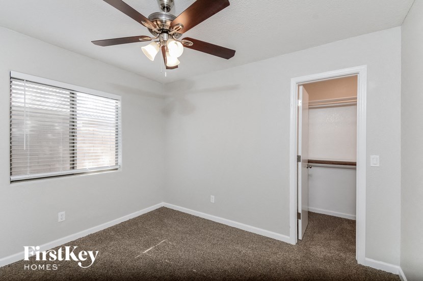 a bedroom with a ceiling fan and a door to a closet