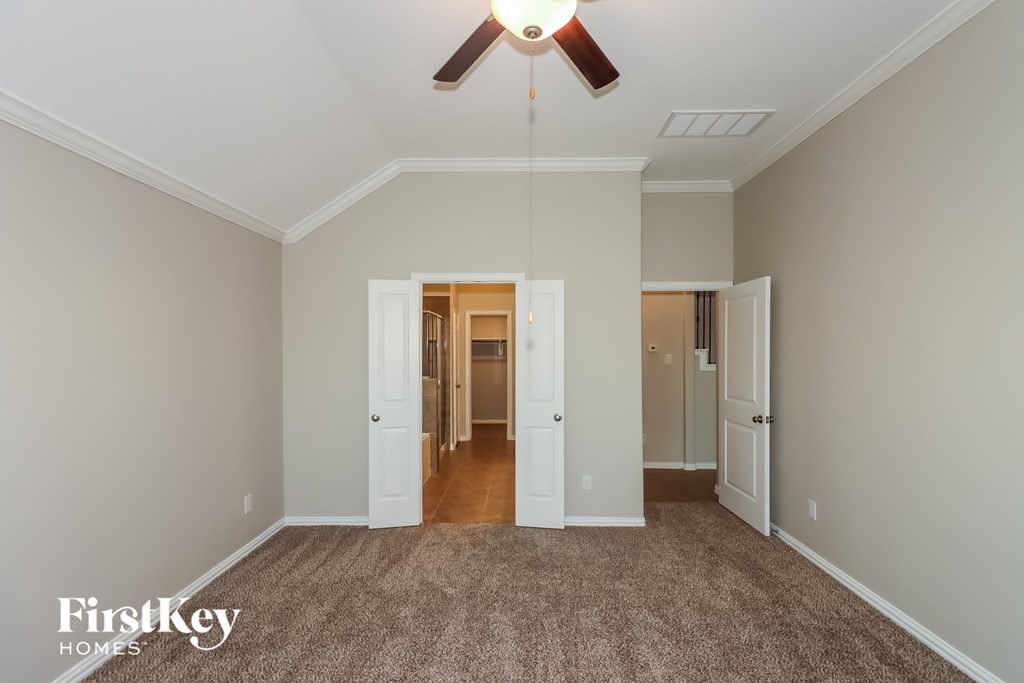 a living room with a ceiling fan and a carpet
