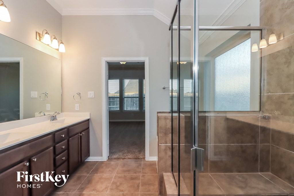 the master bathroom has a large walk in shower and a large vanity