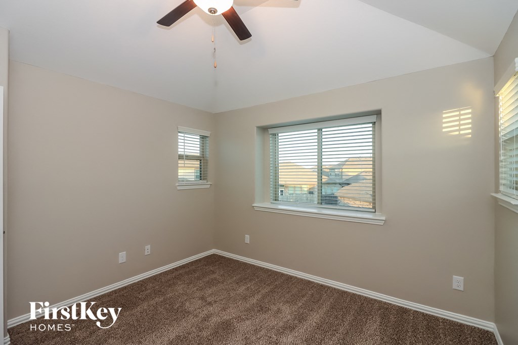 the living room is spacious and has a ceiling fan and two windows
