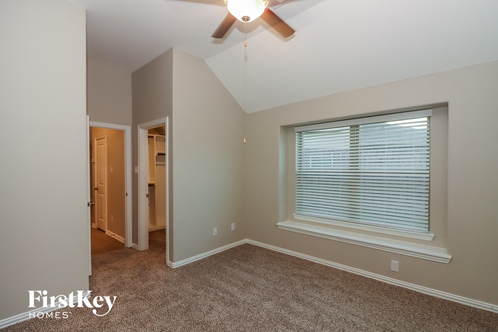 a bedroom with a large window and a ceiling fan