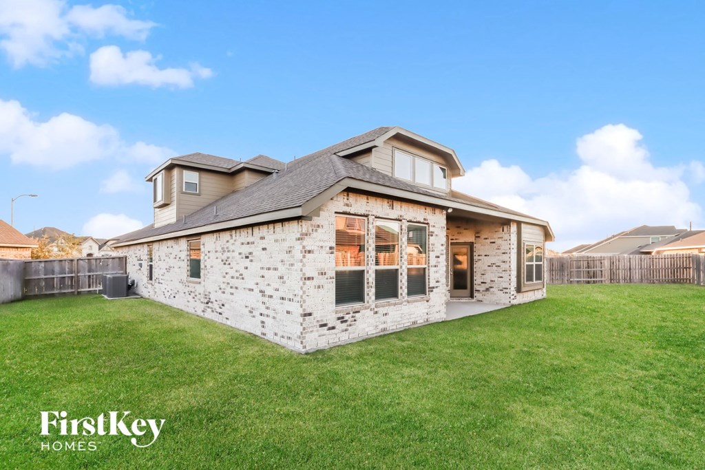 a home with a brick and wood exterior and a grassy yard