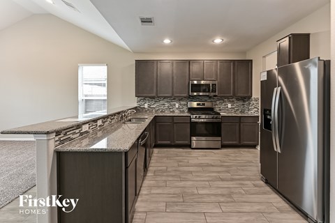 A kitchen with a refrigerator on the right side.