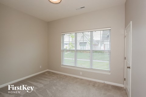 a bedroom with a large window and a carpeted floor