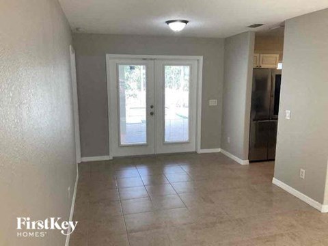 A kitchen area with a refrigerator, cabinets, and a door leading outside.