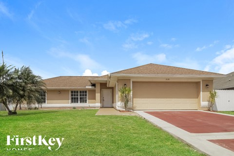 a beige house with a lawn and a driveway