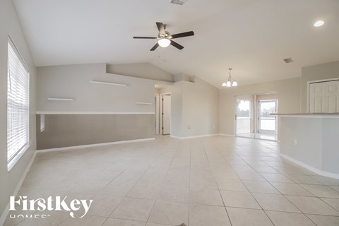 an empty living room with a ceiling fan