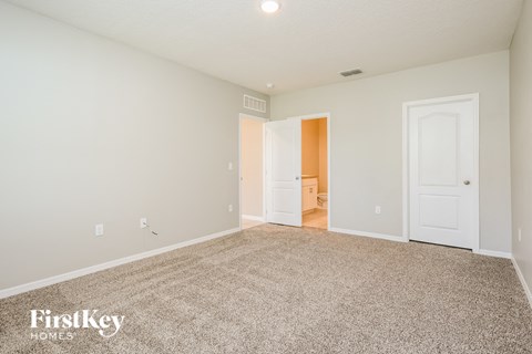 a spacious living room with carpet and a door to the bathroom