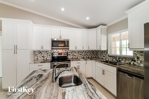 A kitchen with a granite counter top and a stove top oven.