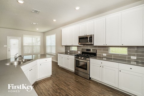 A modern kitchen with white cabinets and stainless steel appliances.