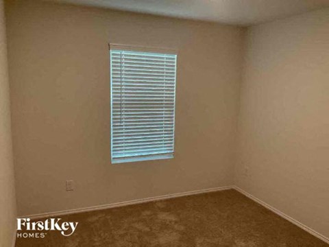 A room with a window covered by white blinds.