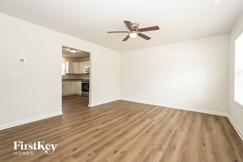 A spacious room with wooden flooring and a ceiling fan.