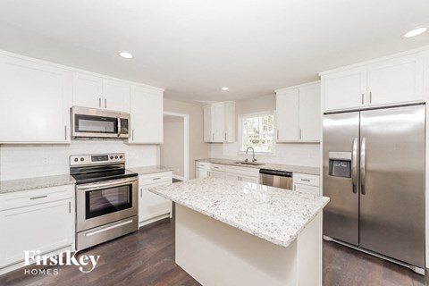A kitchen with white cabinets and a granite countertop.