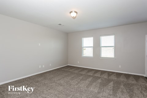 the spacious living room with carpet and two windows