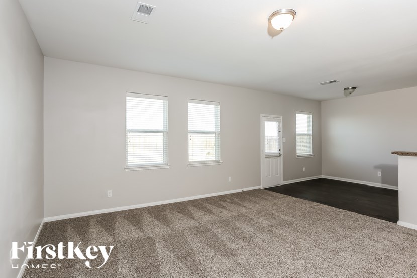 A spacious room with a carpeted floor and a fireplace on the right side.