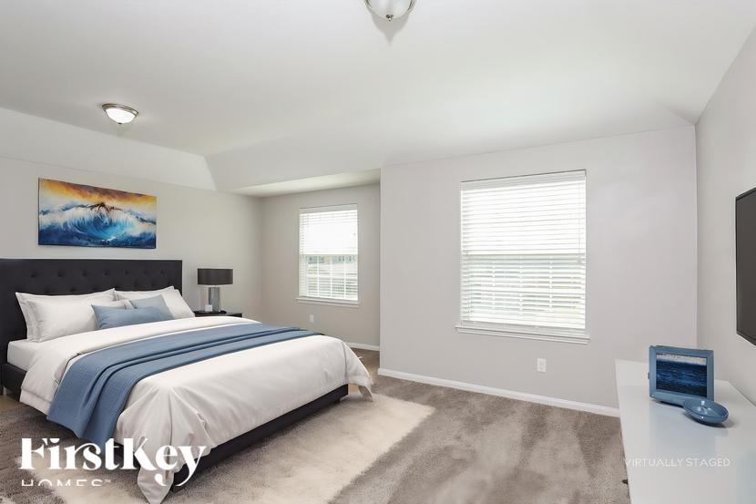 A bedroom with a large bed and a painting on the wall.