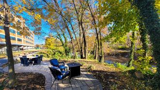 a patio with a table and chairs next to a river