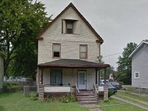 A small, two-story house with a front porch.