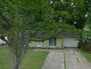 A house with a white door and a tree in front.