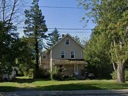 a house on the side of a street with trees