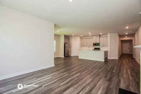 the living room and kitchen of an apartment with wood flooring