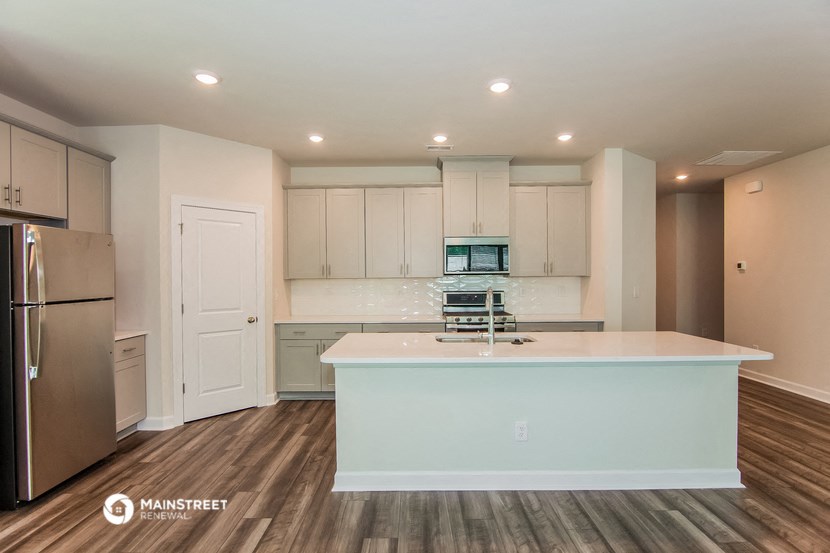 a white kitchen with a large island and stainless steel appliances