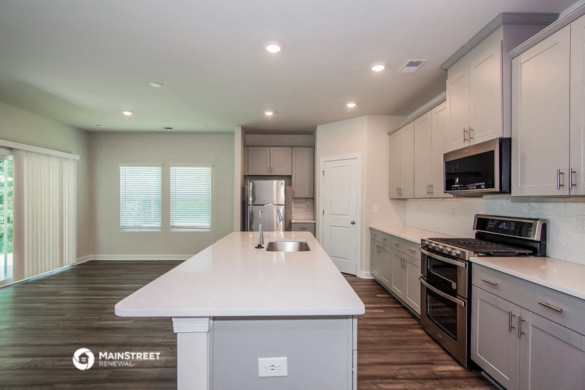 a white kitchen with a large island and stainless steel appliances