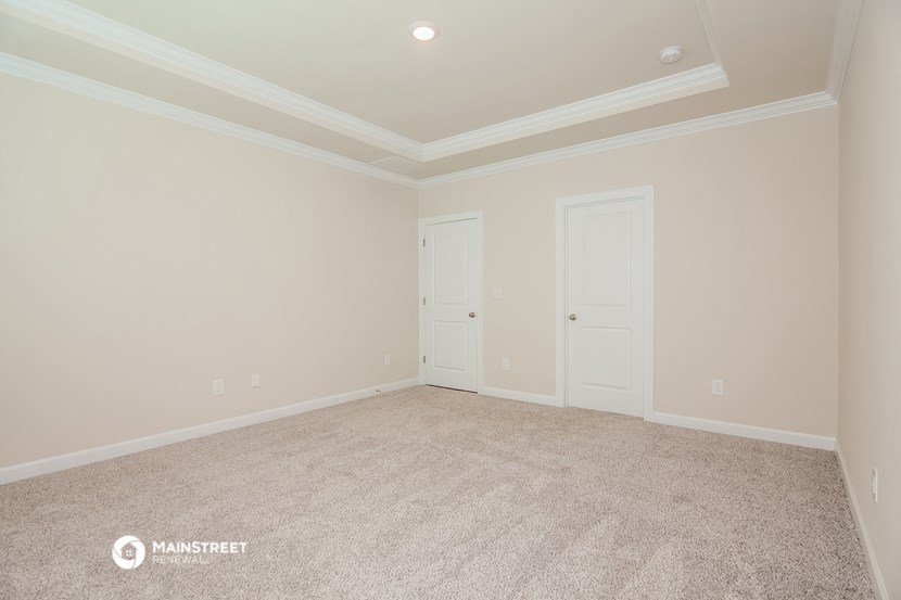 a empty living room with a carpeted floor and two doors