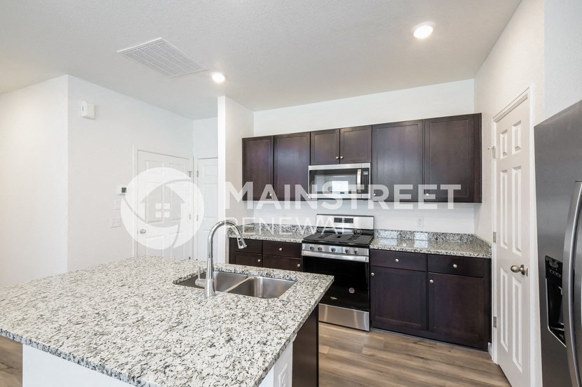 a kitchen with granite counter tops and dark wood cabinets