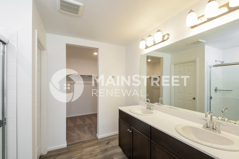a master bathroom with two sinks and a large mirror