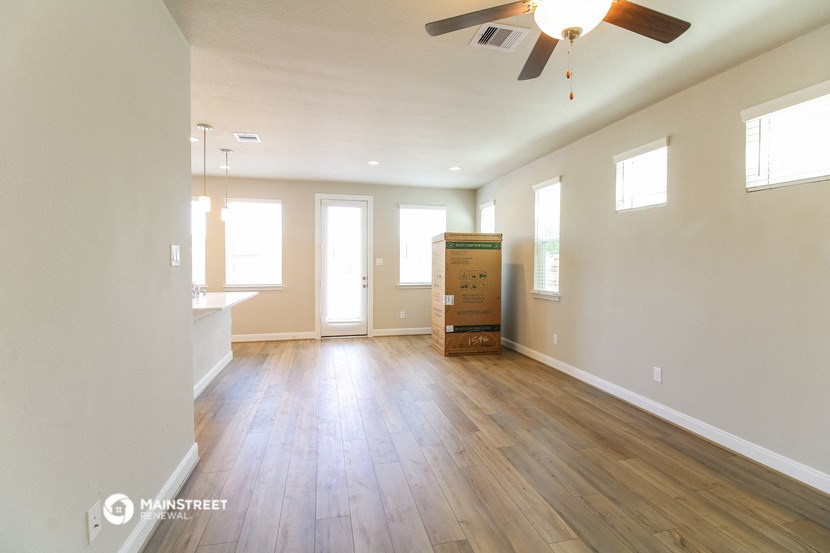 an empty living room with wooden floors and a ceiling fan