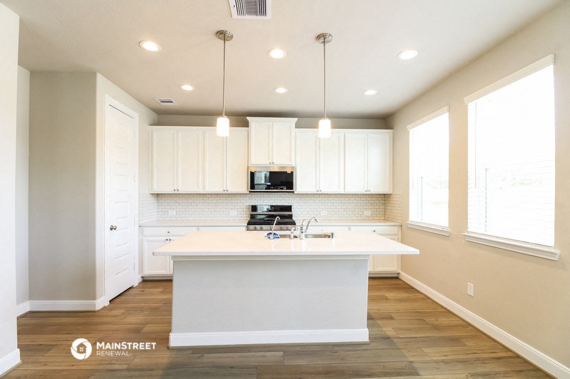 an open kitchen with white cabinets and a white counter top